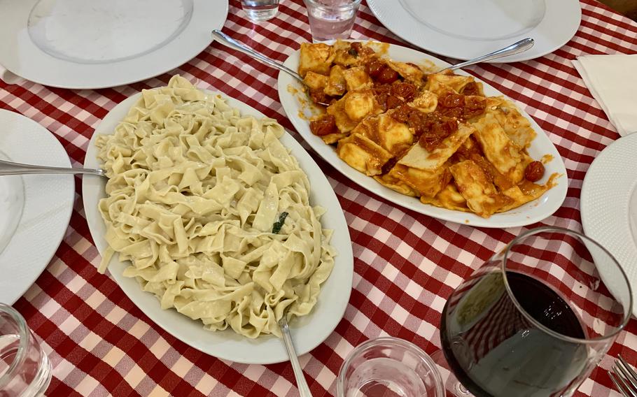 A plate of tagliatelle and a plate of ravioli with tomato sauce.