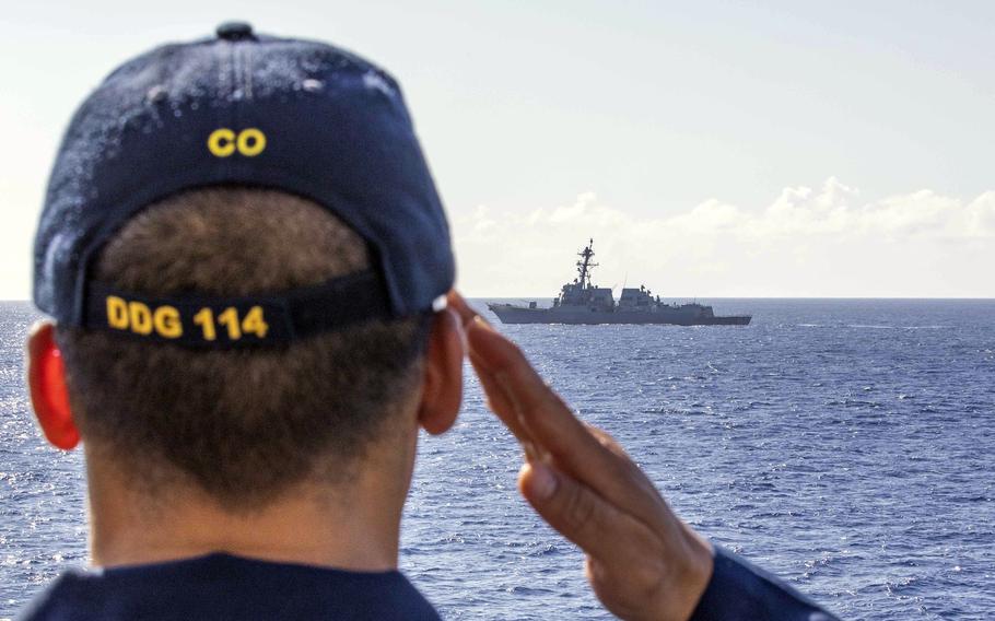 Cmdr. Isaia Infante of the guided-missile destroyer USS Ralph Johnson salutes the USS Rafael Peralta in the South China Sea, Sept. 28, 2023. 