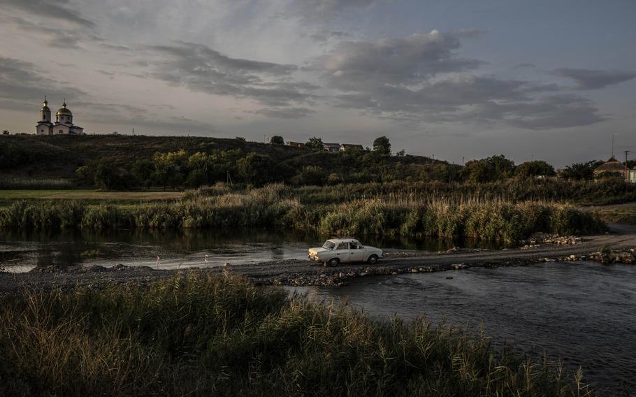 A car leaves the Russian-occupied Kherson region of Ukraine by way of a makeshift bridge. 