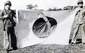 U.S. Marines pose with a battle-torn Japanese flag after capturing the airfield on Guadalcanal in 1942. 