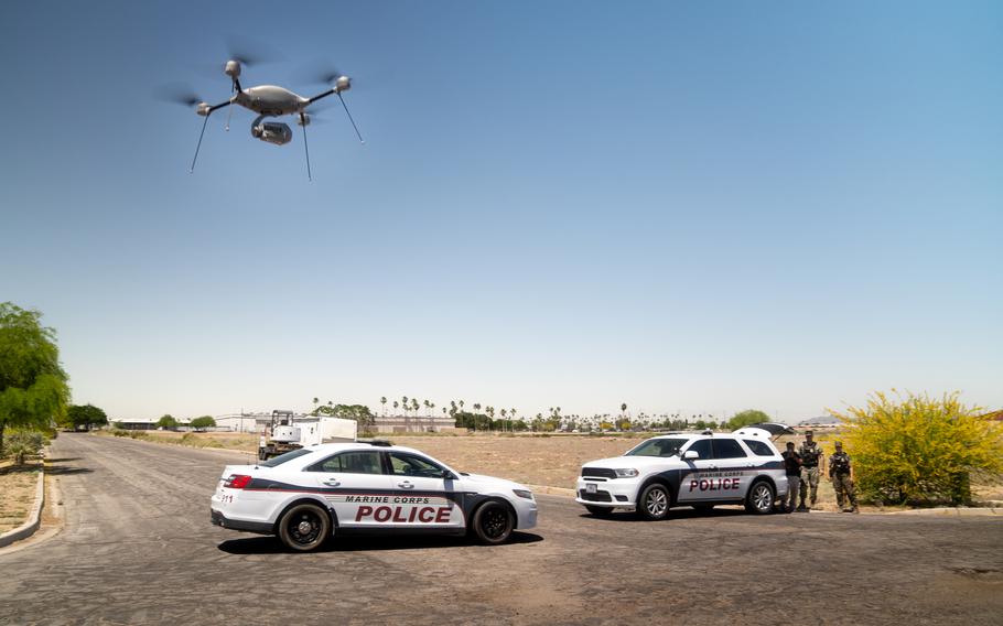 A drone hovers above two police cars.
