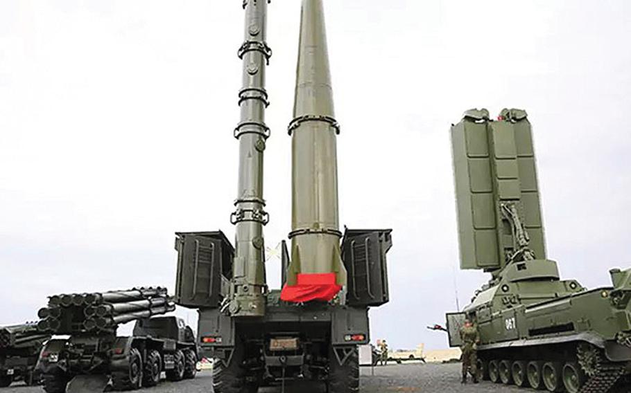 A Russian 9M728 cruise missile container, left, on the truck at center, stands next to a 9M723 short-range ballistic missile. 