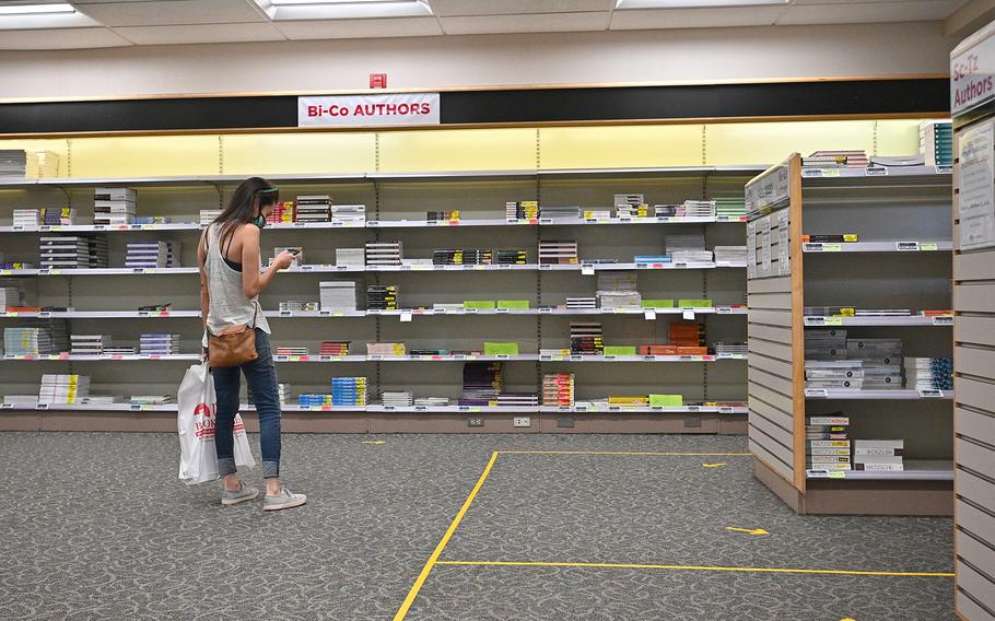 A student checks her phone while shopping for textbooks classes begin amid the coronavirus pandemic on the first day of the fall 2020 semester at the University of New Mexico on Aug. 17, 2020, in Albuquerque.