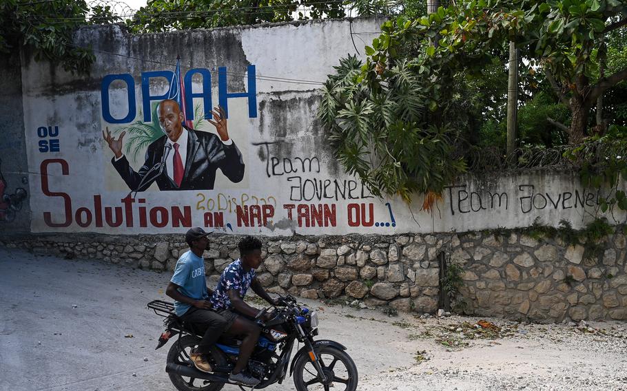 Motorcyclists ride past a mural in Port-au-Prince of the late Haitian President Jovenel Moïse the day before he was laid to rest.