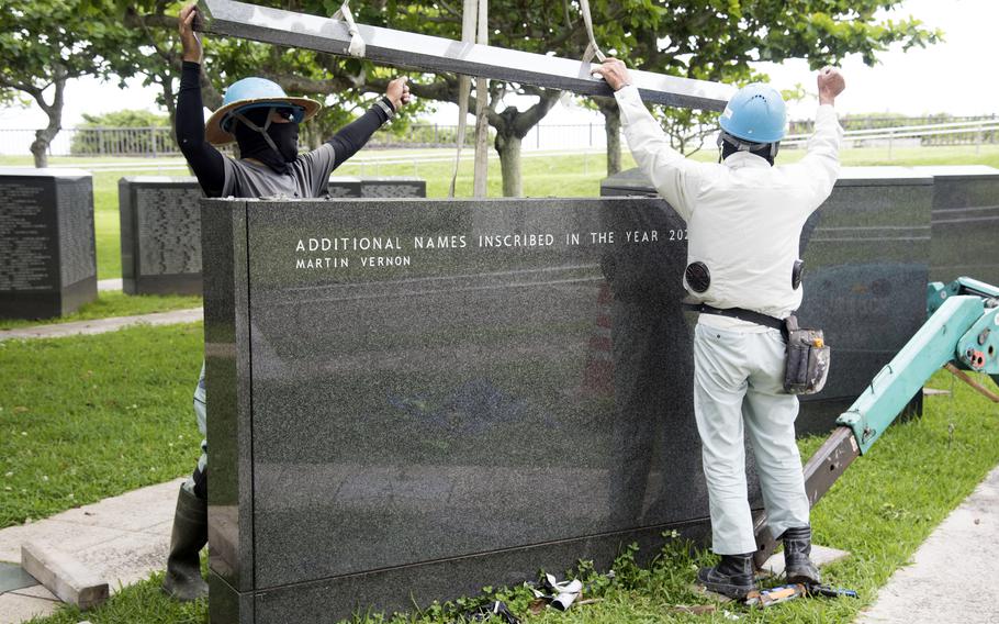 Workers add the name Martin Vernon to a stone monument.