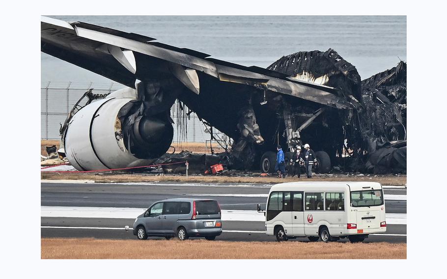 Officials look at the burnt wreckage of a Japan Airlines  passenger plane on the tarmac at Tokyo International Airport at Haneda in Tokyo on Jan. 3, 2024, the morning after the JAL airliner hit a smaller coast guard plane on the ground. 