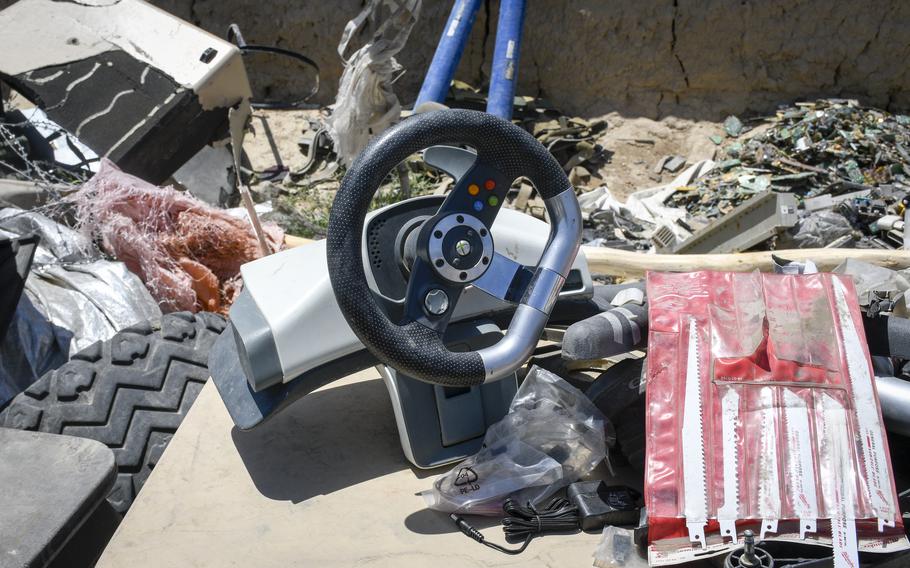 Workers at a trash yard outside Bagram Airfield, Afghanistan, displayed an Xbox controller for driving games on a special table June 5, 2021. A surge of containers and junk have been trucked out of Bagram since May, residents near the base said.