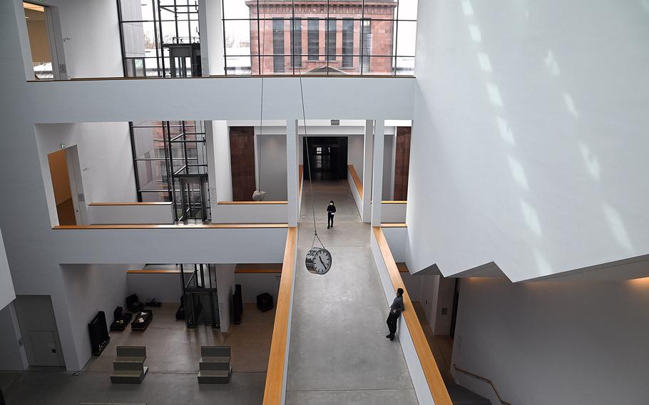 Inside the three-story Hector Bau, the modern, new building of the Kunsthalle Mannheim. The exhibition spaces and galleries of varying sizes, called Kubus, or cubes, are connected by bridges and staircases. The clock that swings over the passageway is part of a piece by Alicja Kwade called The Void of the Moment in Motion. The Kunsthalle’s original art nouveau building can be seen through the window in the background.