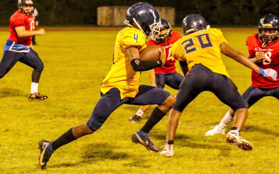 Guam High quarterback Arron Johnson gets an escort from teammate Justin Brantley.