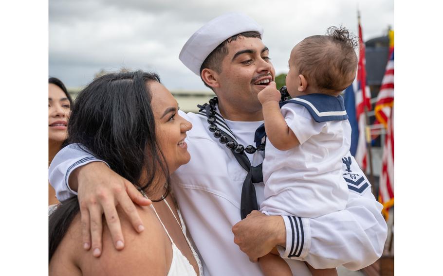 A sailor embraces a baby and a woman