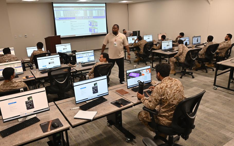 Saudi military personnel sit in front of computers during a class.