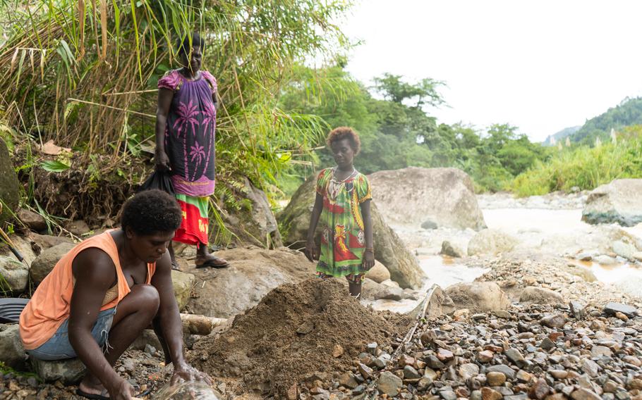 Justina Naviu and her daughter watch a woman pan for gold in the river downstream from the Panguna mine. 