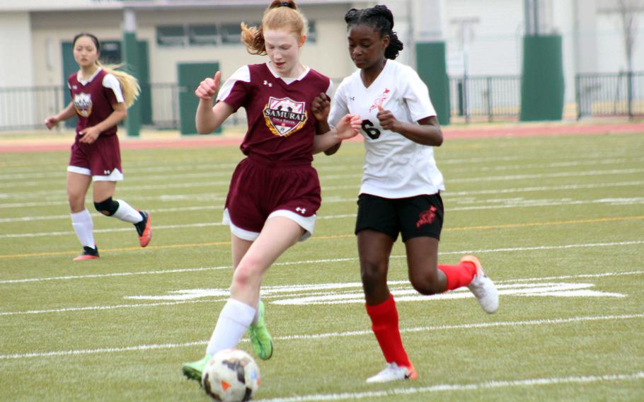 Matthew C. Perry's McKenzie Mitchell and E.J. King's Adrianna Lemons battle for the ball during Saturday's DODEA-Japan soccer match. The Cobras won 3-0.