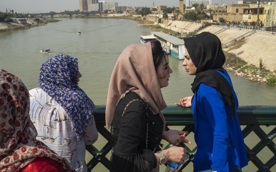 Women stand on the "martyrs' bridge" spanning the Tigris River in Baghdad, Iraq, Friday, Feb. 24, 2023.