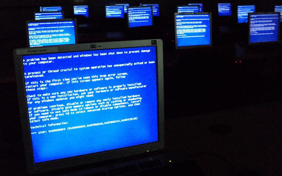 A dark room with several computer screens showing a blue errors screen with white text.