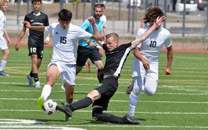 Alconbury’s Ian Barbour comes across the pitch to stop Ansbach’s Chris Roman in the Division III boys title match at the DODEA-Europe soccer championships in Ramstein, Germany, May 22, 2025.  Despite his efforts, the Dragons fell to the Cougars 1-0. At right is Daeveon Brown.