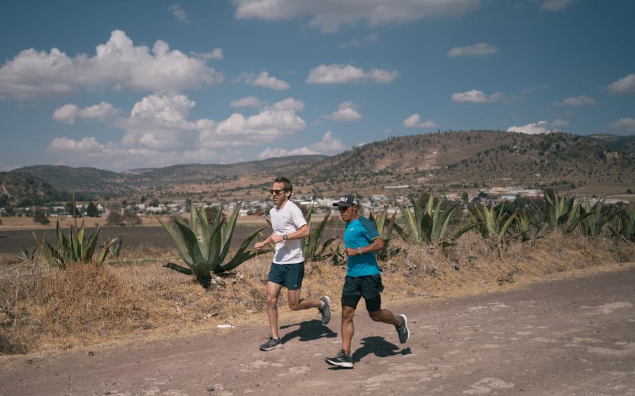 Washington Post reporter Kevin Sieff, left, and Germán Silva run on a dirt road in Tlaxcala on Jan. 18, 2022.
