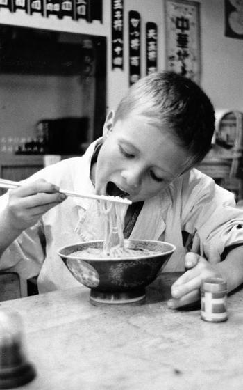 A child eats Soba with chopsticks