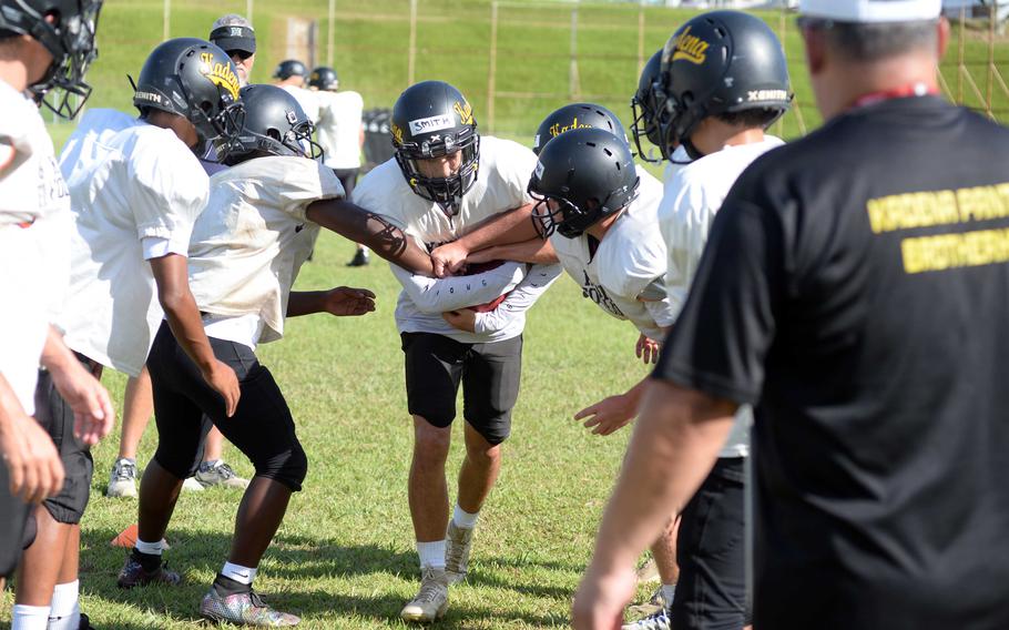 Kadena senior Michael Smith runs the gauntlet of players trying to take the ball from him during Monday's practice.