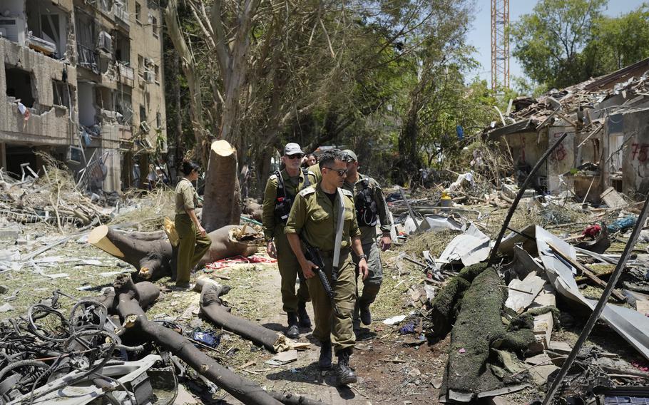 Soldiers walk through debris.
