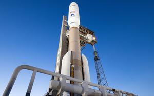 A rocket sits at a space launch site, seen from the base of the rocket.
