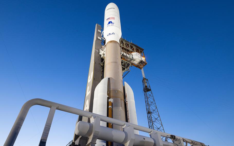 A rocket sits at a space launch site, seen from the base of the rocket.