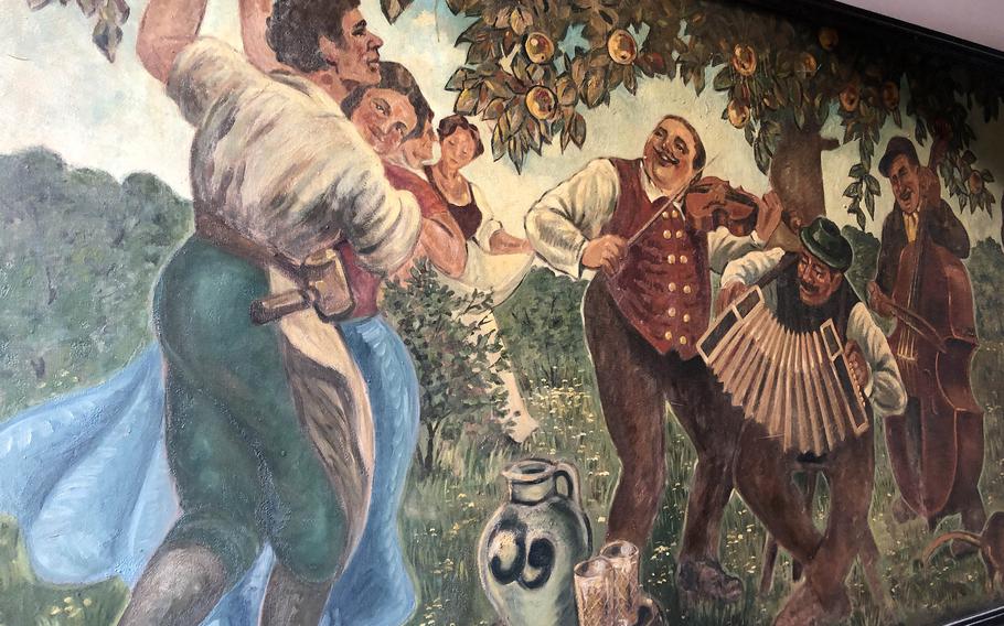 A painting of a couple dancing to the music while enjoying apple wine is one of many large artworks adorning the walls of Zum Gemalten Haus, or painted house, in Frankfurt, Germany. Note the pitcher, called a bembel, and the glasses of apple wine.