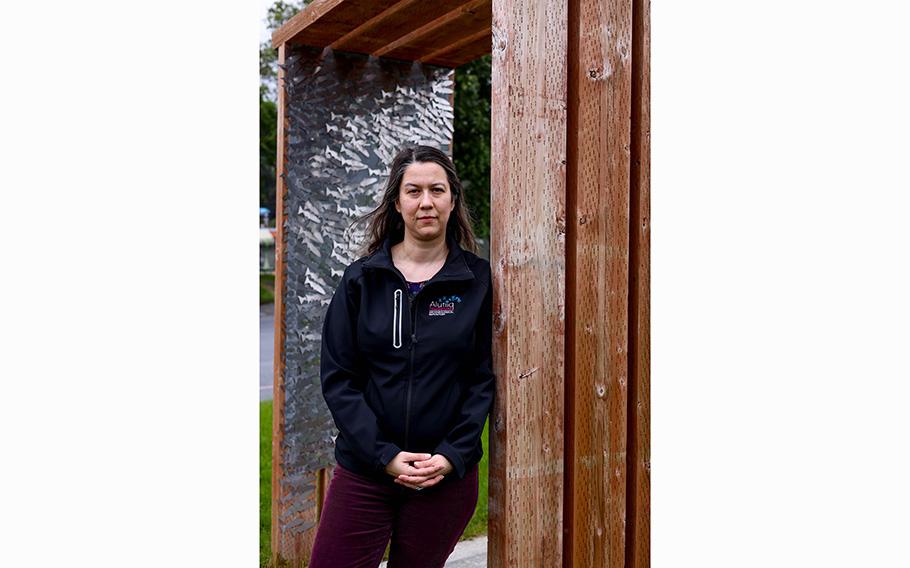Alutiiq Museum executive director April Laktonen Counceller stands by an archway with metal fish representing individual ancestors who have been repatriated to Alaskan tribes for reburial. 