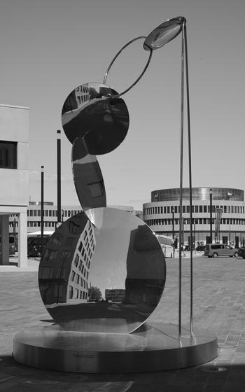 A lens sculpture in a black-and-white photograph features circular shapes stacked on top of each other. 