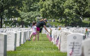 A volunteer places flowers at headstones from the Memorial Flower Foundation in Section 12 of Arlington National Cemetery, Arlington, Virginia, May 26, 2019. Every year over Memorial Day weekend, over 142,000 visitors come to Arlington National Cemetery to honor those who are laid to rest in these hallowed grounds. (U.S. Army photo by Elizabeth Fraser / Arlington National Cemetery / released)