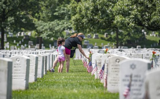 A volunteer places flowers at headstones from the Memorial Flower Foundation in Section 12 of Arlington National Cemetery, Arlington, Virginia, May 26, 2019. Every year over Memorial Day weekend, over 142,000 visitors come to Arlington National Cemetery to honor those who are laid to rest in these hallowed grounds. (U.S. Army photo by Elizabeth Fraser / Arlington National Cemetery / released)
