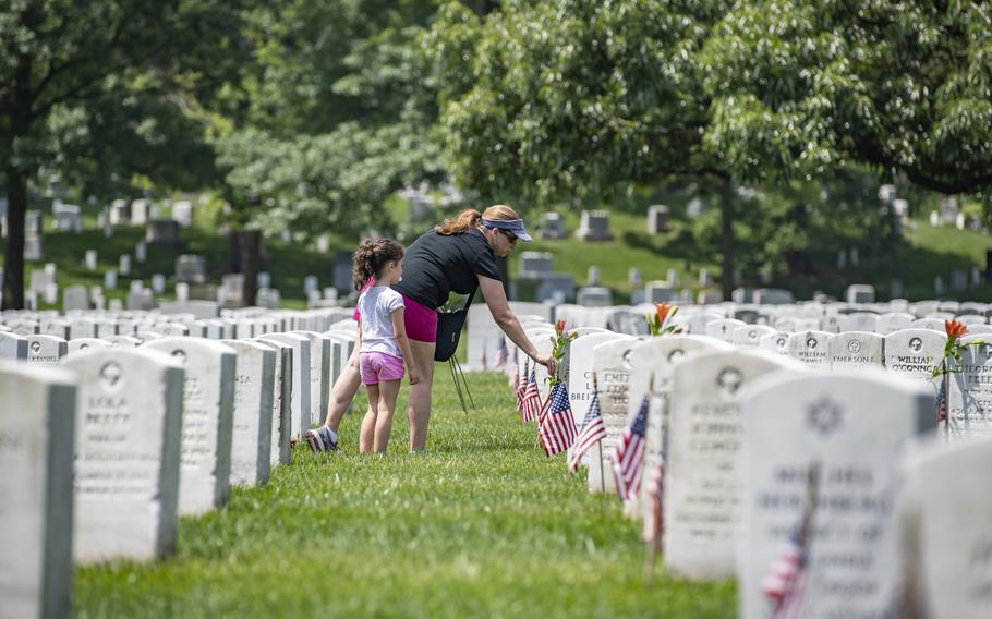 A volunteer with The Memorial Day Flowers Foundation places flowers at headstones at Arlington National Cemetery, Va., on May 26, 2019. Every year during the Memorial Day weekend, more than 142,000 people visit the cemetery to honor those who are laid to rest on the grounds. 