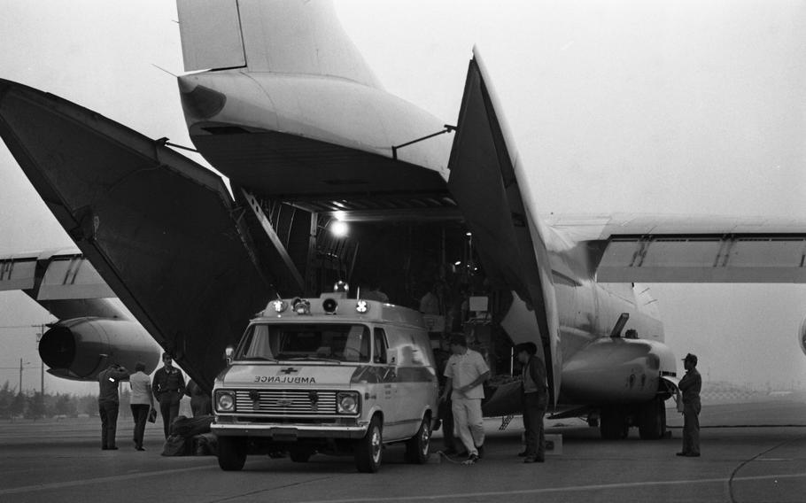 A black and white photo of an ambulance at the opening of a large airplane.