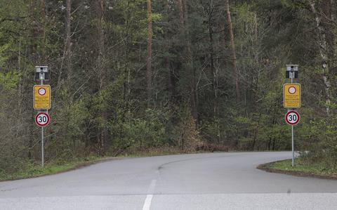 Two road signs flank the entrance to a road, declaring a speed limit of 30 kph.