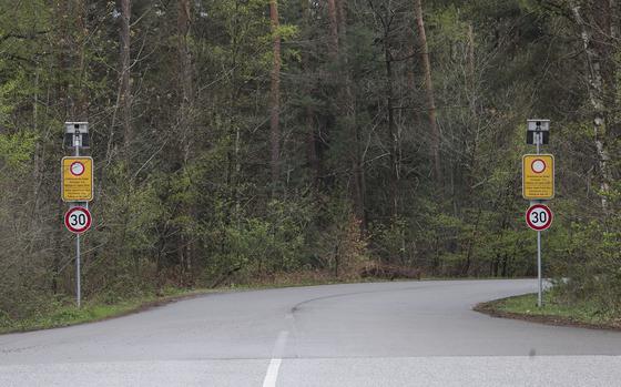 Two road signs flank the entrance to a road, declaring a speed limit of 30 kph.