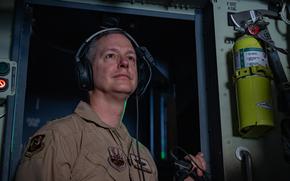 An airman looks out the window of an aircraft.
