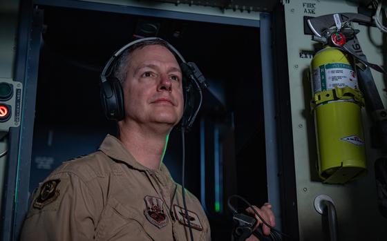 An airman looks out the window of an aircraft.