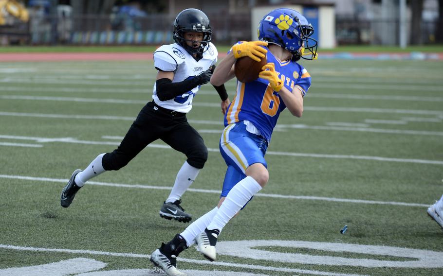 Yokota's Liam Rowell turns upfield with a catch in front of Osan's Anthony Waight-Forrester.