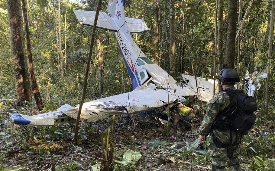 A soldier stands in front of the wreckage of a Cessna C206, Thursday, May 18, 2023, that crashed in the jungle of Solano in the Caqueta state of Colombia.  