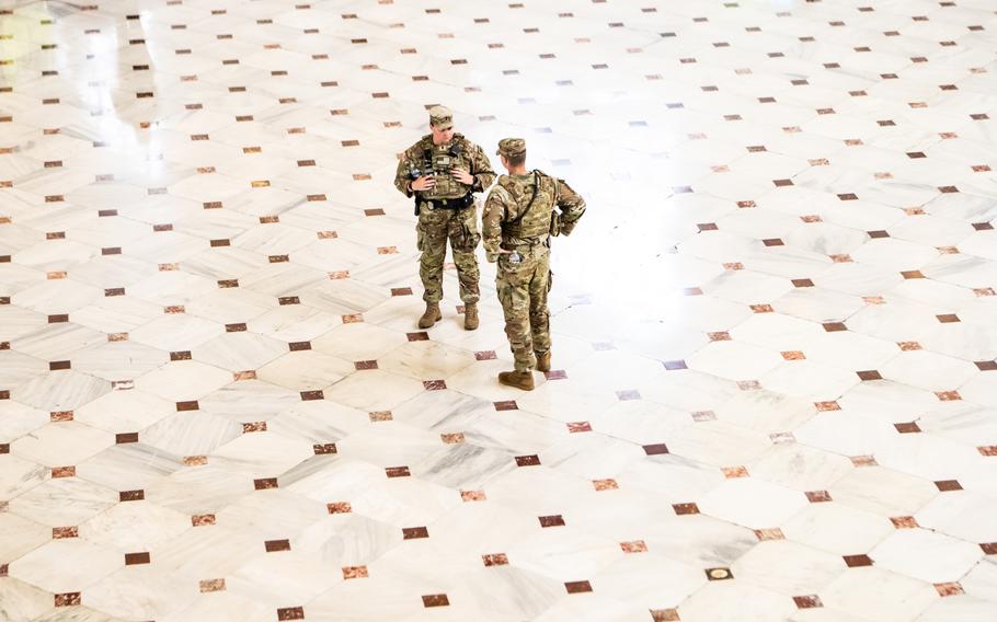 Two male soldiers seen from above in an otherwise empty space of floor.