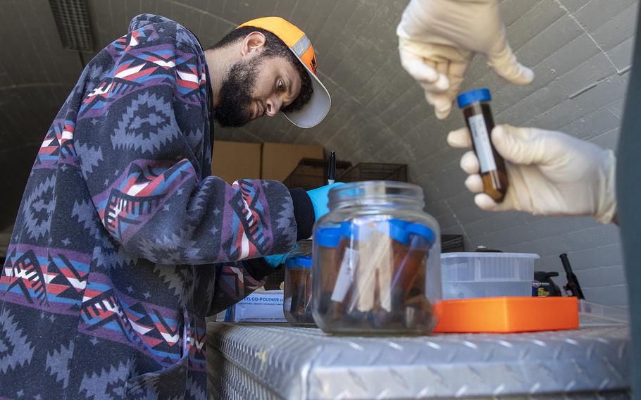 U.S. Geological Survey biologist Jared Heath, left, works with Robert Fisher to extract drops of ethanol from vials containing invertebrates, part of Fisher’s 25-year collection inside a WWII munitions bunker on the former El Toro Marine Corps Air Station, on Wednesday, Dec. 14, 2022, in Irvine, Calif.