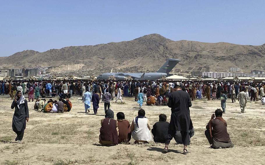 In this Aug. 16, 2021, file photo hundreds of people gather near a U.S. Air Force C-17 transport plane along the perimeter at the international airport in Kabul, Afghanistan. 