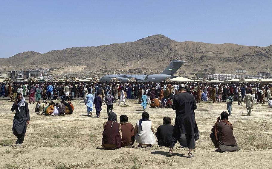 In this Aug. 16, 2021, file photo hundreds of people gather near a U.S. Air Force C-17 transport plane along the perimeter at the international airport in Kabul, Afghanistan. 