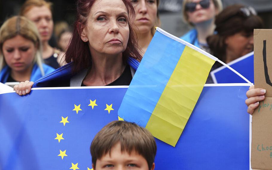 Demonstrators hold EU and Ukrainian flags outside of an EU summit in Brussels, Thursday, June 23, 2022. 