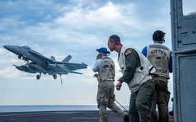 Landing signal officers signal an F/A-18E Super Hornet from the flight deck of USS Harry S. Truman, July 30, 2022.  A Super Hornet jet was swept overboard from the USS Harry S. Truman in the Mediterranean Sea July 8, during unexpected heavy weather.