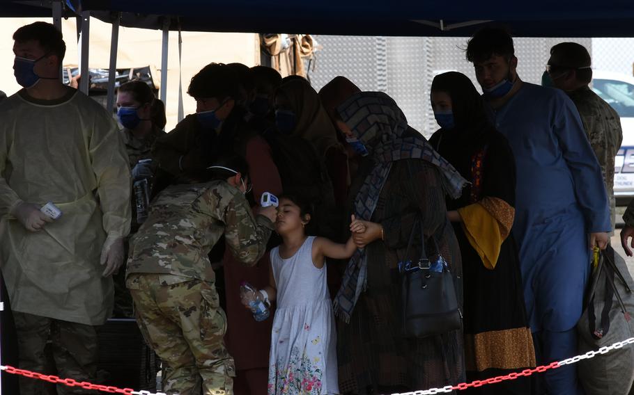 A little girl gets her temperature checked after arriving on a flight carrying Afghan evacuees to Ramstein Air Base, Germany, on Saturday, Aug. 21, 2021. Evacuees undergo a health screening as soon as they get off the plane.