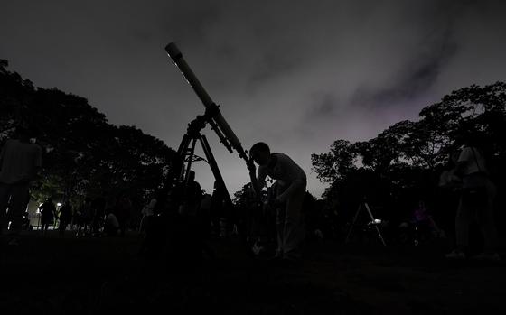FILE - A girl looks at the moon through a telescope in Caracas, Venezuela, on Sunday, May 15, 2022. The best day to spot five planets, Mercury, Jupiter, Venus, Uranus and Mars, lined up in the night sky is Tuesday, March 28, 2023, right after sunset. The five-planet array will be visible from anywhere on Earth, as long as you have clear skies. (AP Photo/Matias Delacroix)