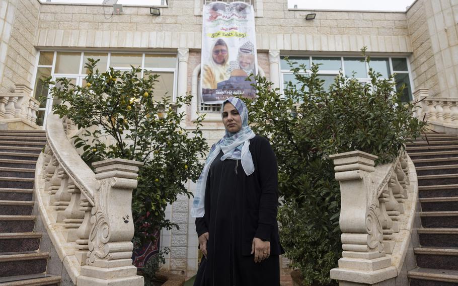 Mona Abdel Jabbar stands below a poster of her son, Tawfic, pictured next to the late Yasser Arafat, on Jan. 24, 2024. 