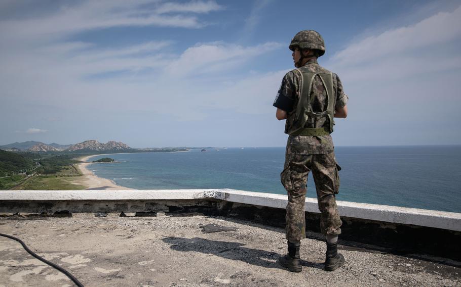 A soldier stands at the Goseong observatory as he waits for a convoy of buses carrying participants of an inter-Korean family reunion making its way through the Demilitarized Zone (DMZ) towards North Korea (background), in Goseong, South Korea, on Aug. 20, 2018.