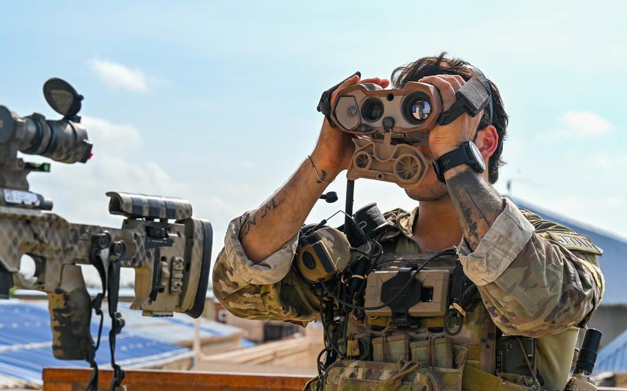 A soldier looks through binoculars